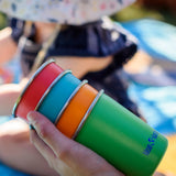 Four cups from the Klean Kanteen Kid cups four in the Beach ball colour way in a hand.
