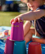 Child stacking the Klean Kanteen stainless steel kid cups in the gum drops colour way on top of each other. 