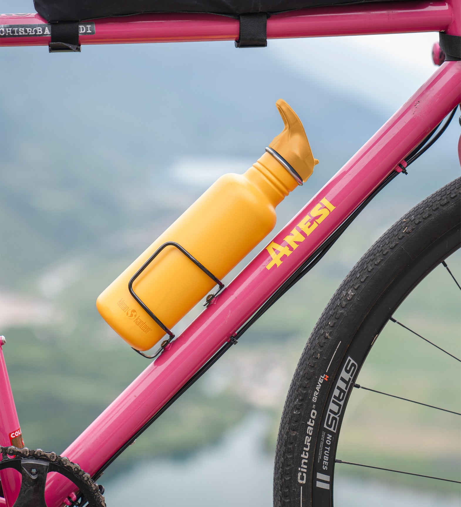 Golden yellow Klean Kanteen bottle with Flip Seal Sports Cap mounted on a bicycle during a ride