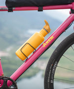 Golden yellow Klean Kanteen bottle with Flip Seal Sports Cap mounted on a bicycle during a ride