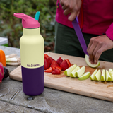 Klean Kanteen Rise Insulated Classic Bottle with Flip Seal Cap in limited edition Wax Yellow on an outdoor picnic table. 