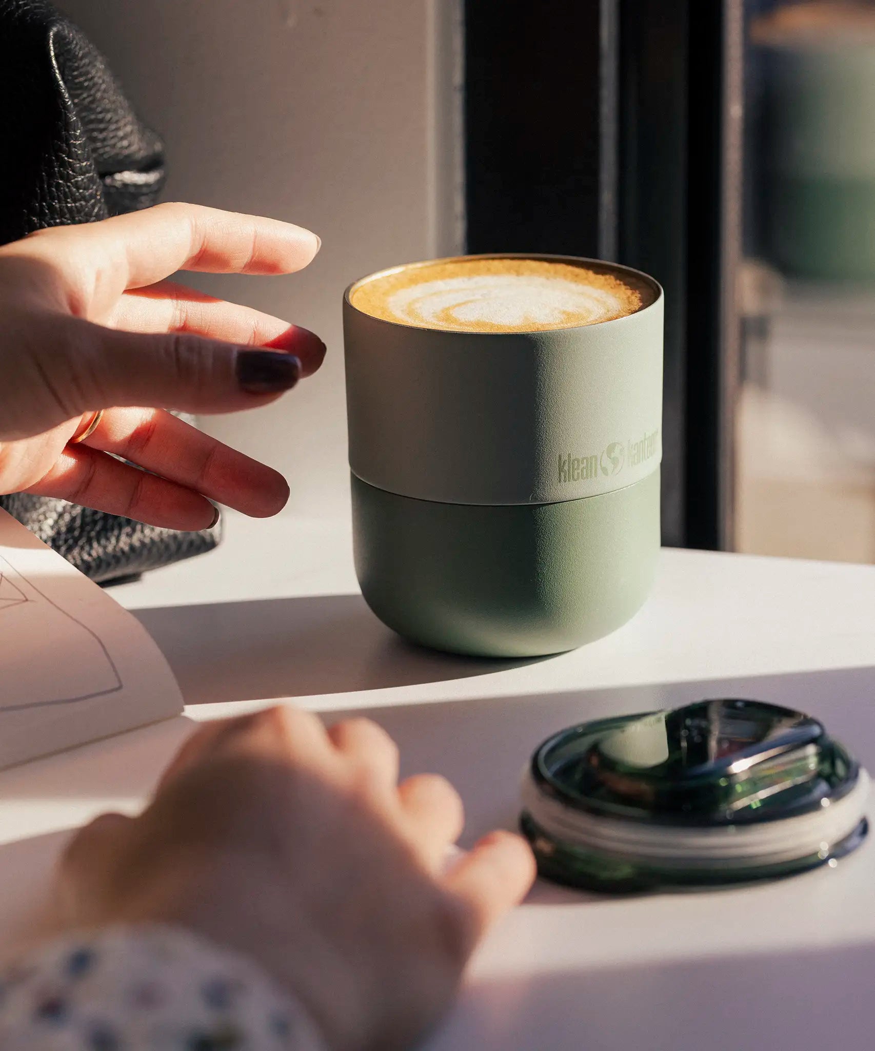 A klean Kanteen sea spray lowball tumbler next to the rise slide lid showing the silicone ring around the cap