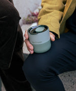 Man holding a Klean Kanteen sea spray green lowball rumbler with the rise slide lid on top and fully closed