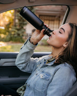 Woman sat in a car drinking from a Klean Kanteen stainless steel drinks bottle with a sports lid
