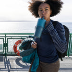A woman sipping the straw on the brittany blue coloured 26oz Klean Kanteen rise tumbler. 