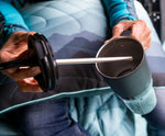A close up of a person's hand lifting the straw lid out of a black 26oz handled Klean Kanteen rise tumbler.