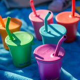 Six colours of Klean Kanteen 10oz/296ml Steel Kid Cups with Straw Lids placed on a blue blanket.