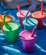 Six colours of Klean Kanteen 10oz/296ml Steel Kid Cups with Straw Lids placed on a blue blanket.