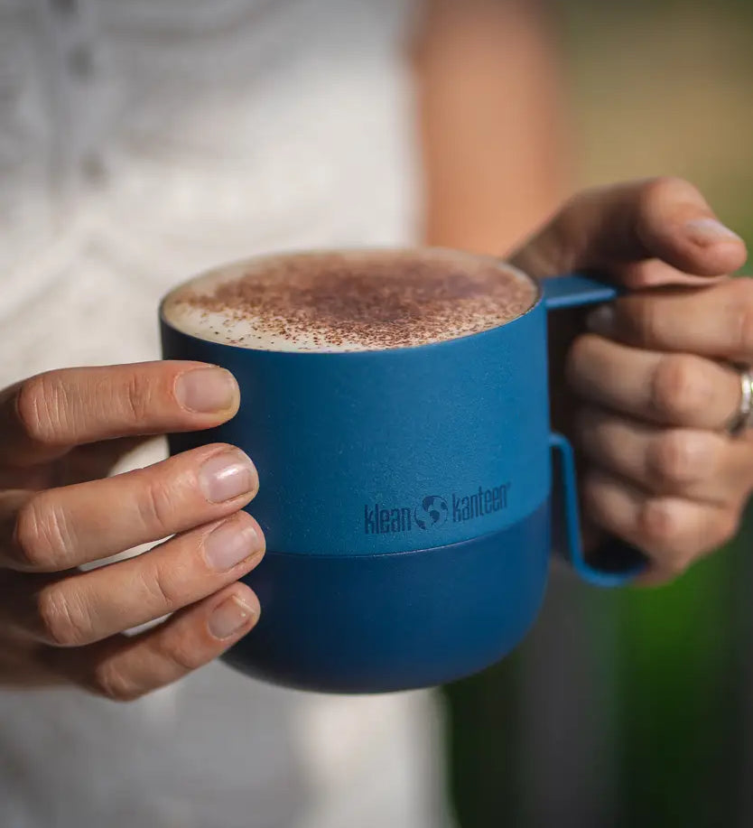 Adult holding a stellar blue 14oz Klean Kanteen stainless steel mug with handle filled with coffee