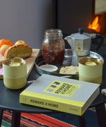 2 Klean Kanteen stainless 8oz tumblers in wax yellow with their lids on top standing on a wooden table with breakfast items 