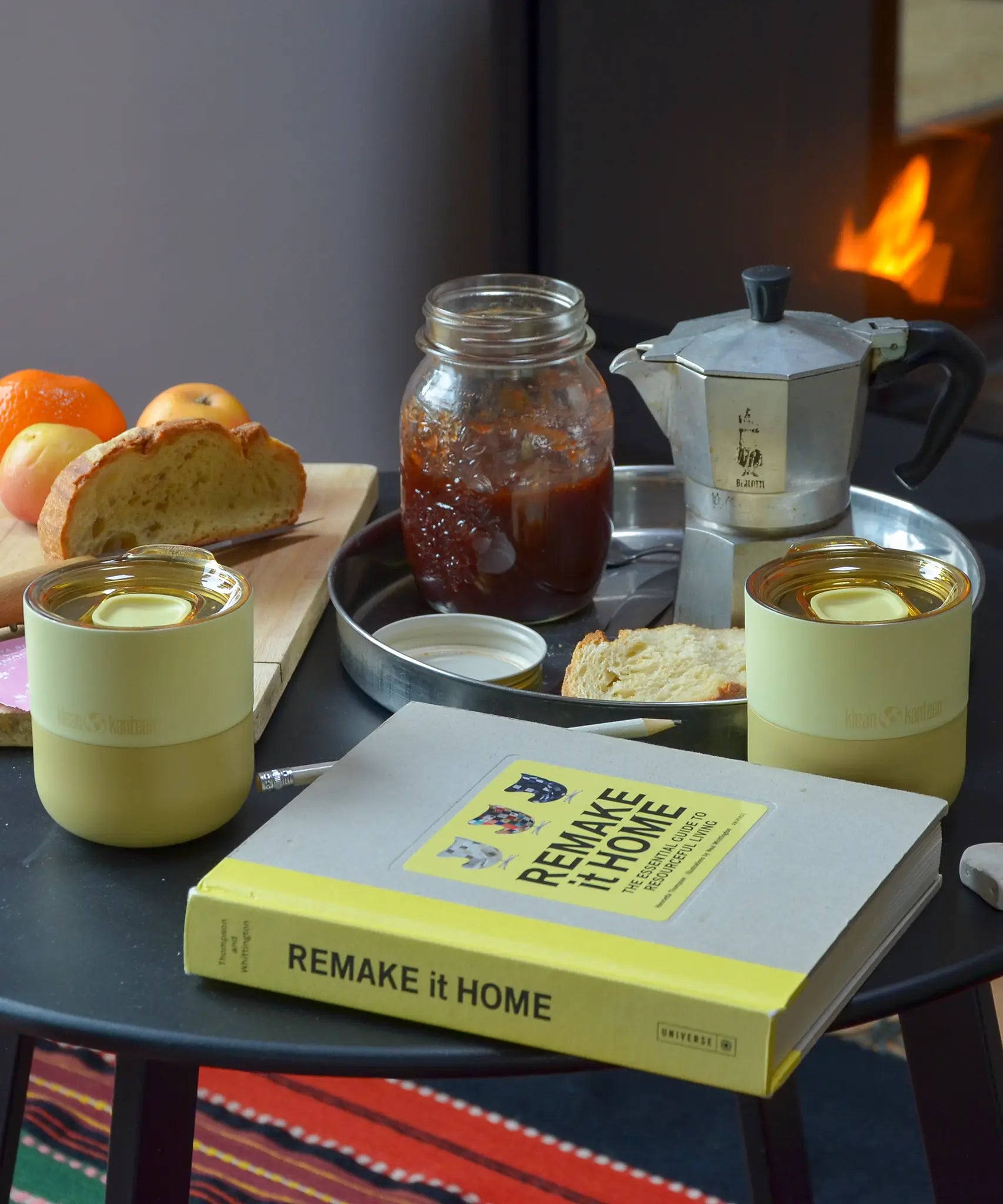 2 Klean Kanteen stainless 8oz tumblers in wax yellow with their lids on top standing on a wooden table with breakfast items 
