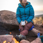 An adult sat outside by a fire