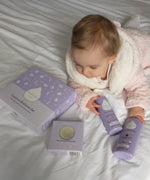 A baby lying on a bed and holdong the kokoso coconut oil baby lotion and body wash from the coconut bathtime set available at Babipur.
