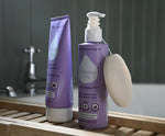 Kokoso Coconut Bathtime Organic Baby Gift Set in its purple and white gift box sitting on a backdrop of large Green leaves