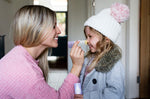 Close up of a woman holding up a Kokoso organic baby balm stick to a child's nose