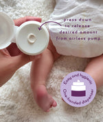 An adult hand holding the  tube of Kokoso organic coconut oil Happy Nappy Cream above a baby and showing the one handed dispenser feature.  Kokoso's range of organic  coconut oil baby care is available at Babipur. 