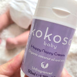 A close up of an adult hand holding the  tube of Kokoso organic coconut oil Happy Nappy Cream available at Babipur. 