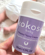 A close up of an adult hand holding the  tube of Kokoso organic coconut oil Happy Nappy Cream available at Babipur. 