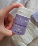 A close up of an adult hand holding the  tube of Kokoso organic coconut oil Happy Nappy Cream showing the size of the tube available at Babipur