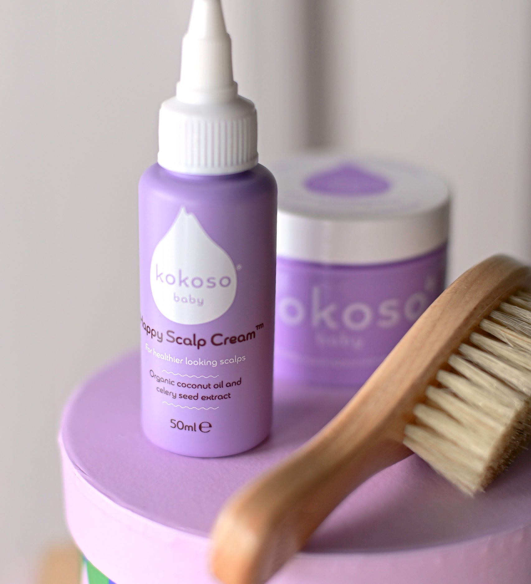 Kokoso Happy Scalp Cream in a 50ml container next to a small tub of Kokoso organic coconut oil and hairbrush. The Kokoso baby care range is available at Babipur.