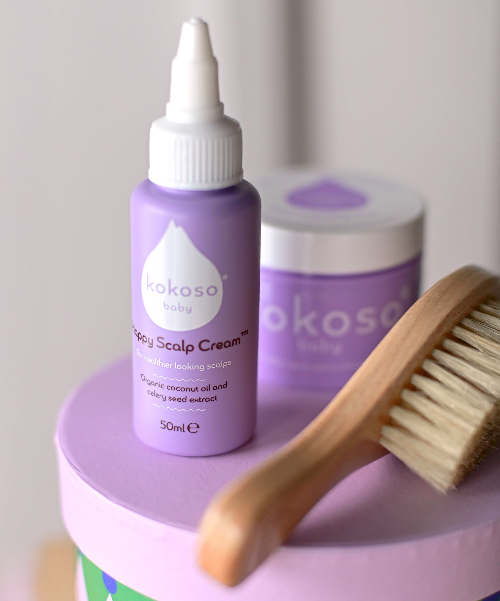 Kokoso Happy Scalp Cream in a 50ml container next to a small tub of Kokoso organic coconut oil and hairbrush. The Kokoso baby care range is available at Babipur.