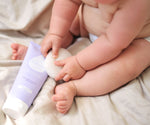 Chubby baby sits on sheet