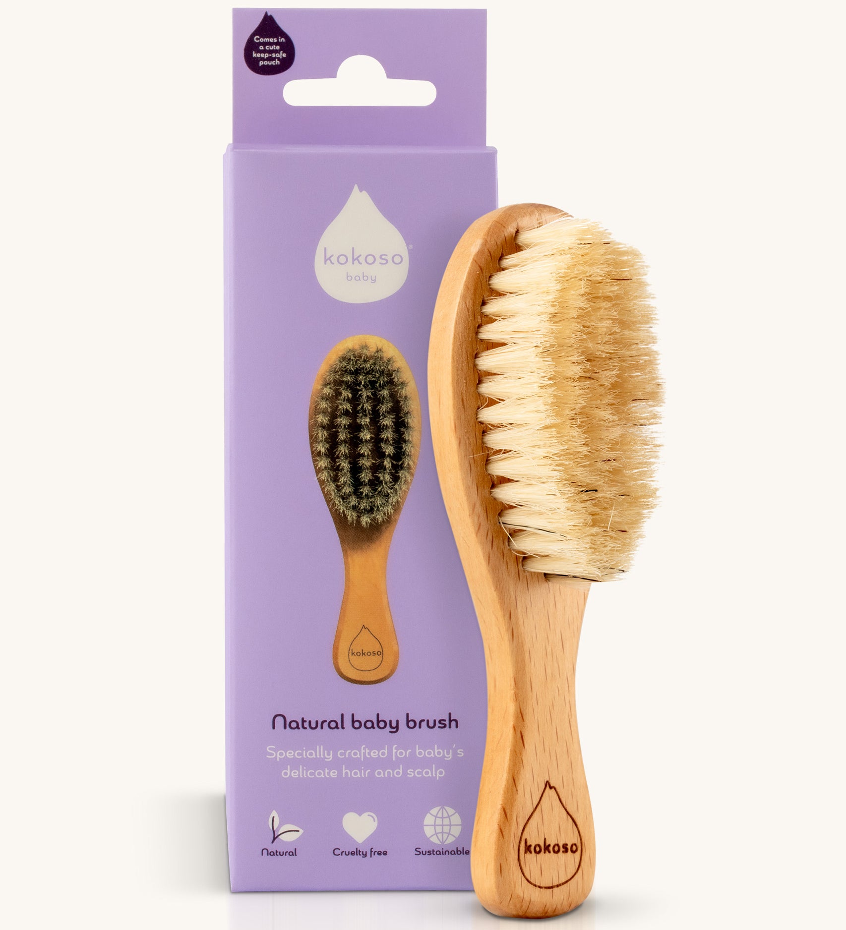 The Kokoso Natural Baby Hairbrush available at Babipur standing next to it's purple branded packaging. Features a wooden handle and soft natural bristles