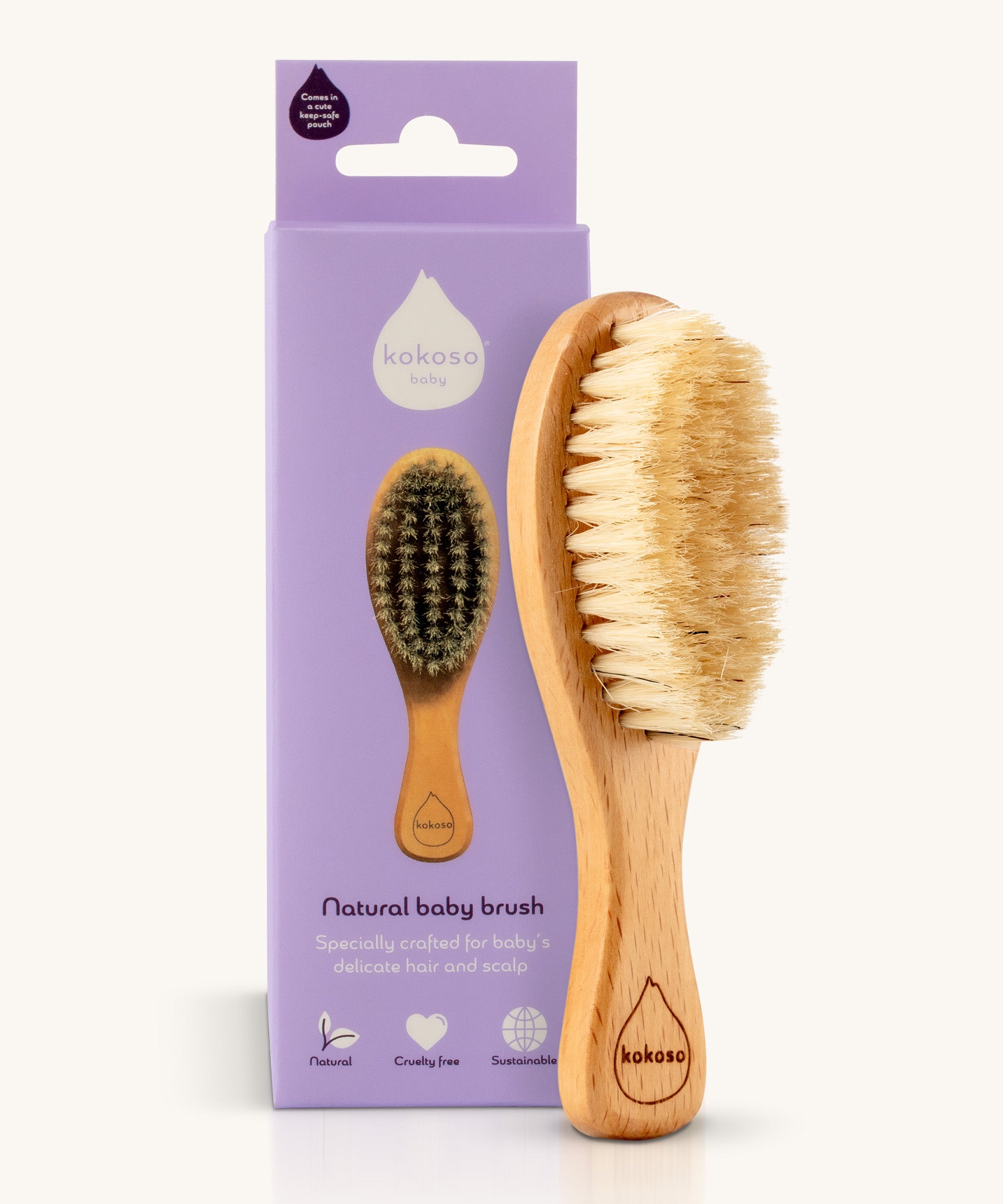 The Kokoso Natural Baby Hairbrush available at Babipur standing next to it's purple branded packaging. Features a wooden handle and soft natural bristles