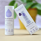 Kokoso unfragranced baby soft balm stick available at Babipur. with a blurred plant in the background.