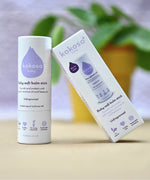 Kokoso unfragranced baby soft balm stick available at Babipur. with a blurred plant in the background.