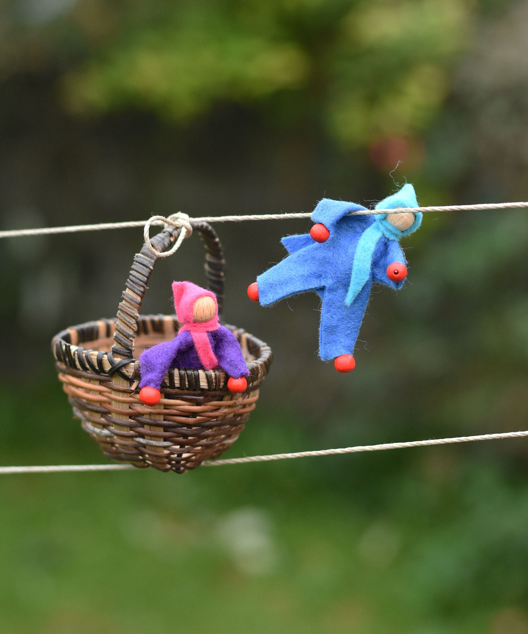 Blue and purple felt Kraul Little Passenger Dolls placed on the Kraul cable car kit. One is holding onto the string and the other is placed in the basket.