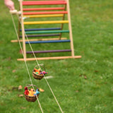 Two wicker baskets travelling along on the rope of the Kraul DIY Basket Cable Car STEM Kit.  An adult's hand can be seen turning the wheel control in the background. 