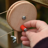 A close up of an adult's hand turning the wheel of the Kraul DIY Basket Cable Car STEM Kit.