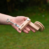 An adult's hand holding the clamp that they have assembled from the  Kraul DIY Basket Cable Car STEM Kit in their hand.