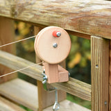 The clamp from the Kraul DIY Basket Cable Car STEM Kit attached to a mud kitchen outdoors.