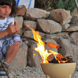 A child sitting by a fire lit in the Kraul children's ceramic fire bowl. Kraul is available at Babipur their range of kits let children discover a world of wonder with Kraul STEM science kits and educational toys.
