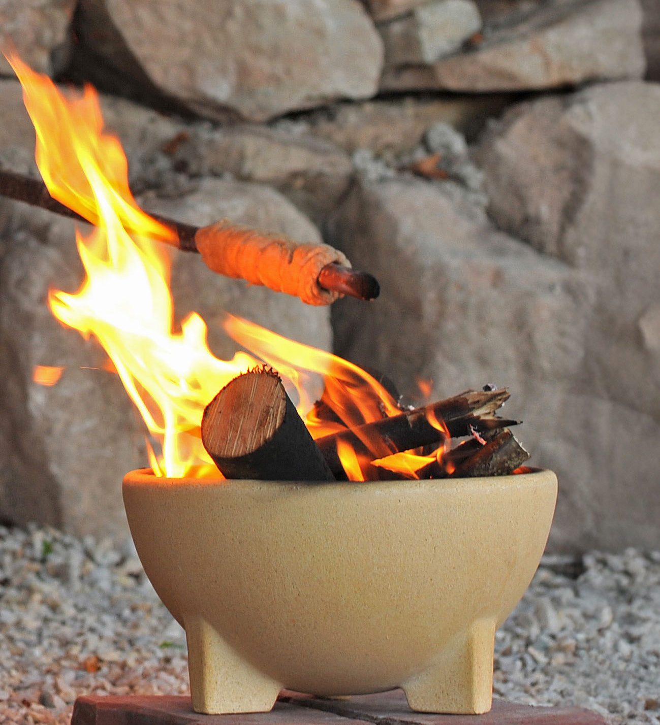 A fire lit in the Kraul ceramic fire bowl filled with logs and sticks. Kraul is available at Babipur their range of kits let children discover a world of wonder with Kraul STEM science kits and educational toys.