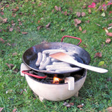 Sausages placed in a Kraul cooking pan that has been placed on a lit fire in the Kraul ceramic fire bowl. Kraul is available at Babipur their range of kits let children discover a world of wonder with Kraul STEM science kits and educational toys.