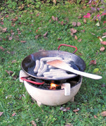 Sausages placed in a Kraul cooking pan that has been placed on a lit fire in the Kraul ceramic fire bowl. Kraul is available at Babipur their range of kits let children discover a world of wonder with Kraul STEM science kits and educational toys.
