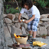 A child breaking an egg into the Kraul Cooking pan that has been placed on a lit fire in the Kraul ceramic fire bowl.  Kraul is available at Babipur their range of kits let children discover a world of wonder with Kraul STEM science kits and educational toys.