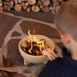 A child sitting by a fire lit in the Kraul children's ceramic fire bowl. Kraul is available at Babipur their range of kits let children discover a world of wonder with Kraul STEM science kits and educational toys.