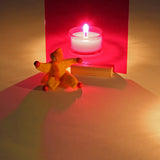 A candle behind a red window from the Kraul light and colour set creating a relaxing red shadow