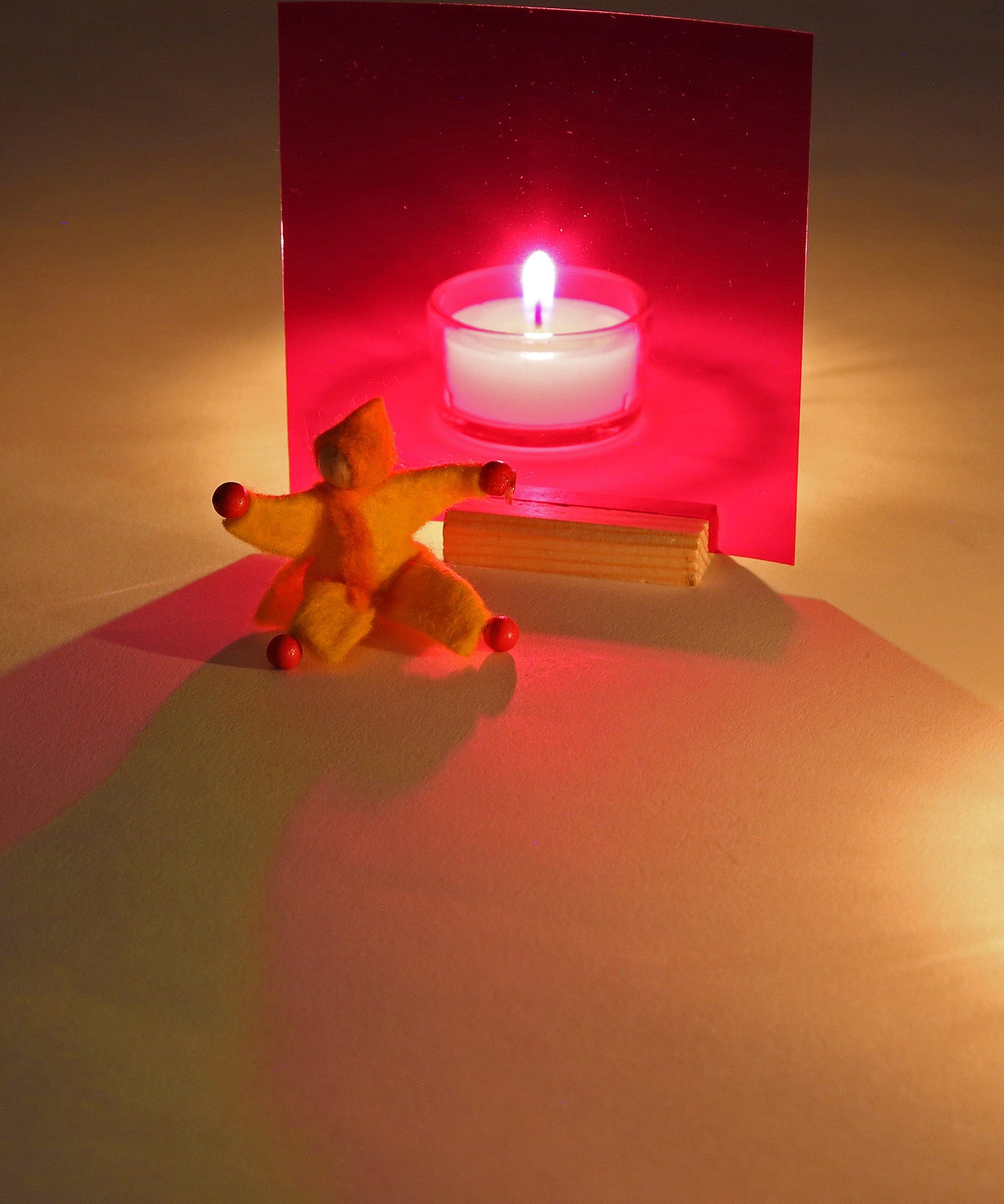 A candle behind a red window from the Kraul light and colour set creating a relaxing red shadow