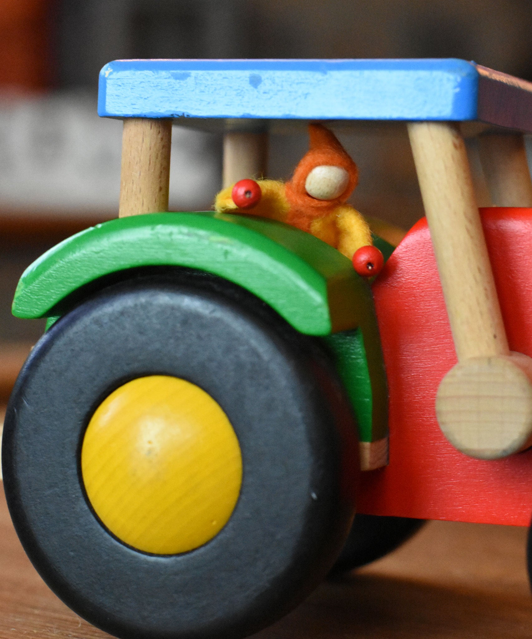 A Kraul felt passenger pose-able doll placed in the cab of the Bajo wooden tractor toy. These pose-able dolls are perfect to fit inside smaller toy vehicles and for use with the Kraul cable cars.