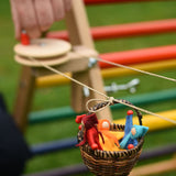 A close up of one of the wicker baskets on the rope of the Kraul DIY Basket Cable Car STEM Kit.  An adult's hand can be seen turning the wheel control in the background. 
