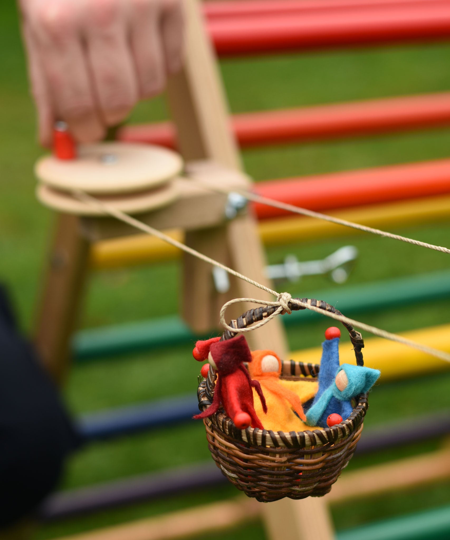 A close up of one of the wicker baskets on the rope of the Kraul DIY Basket Cable Car STEM Kit.  An adult's hand can be seen turning the wheel control in the background. 