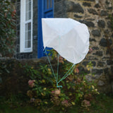 A DIY paper parachute made using the Kraul parachute kit floating down in mid air.  Kraul offers a range of thoughtful science toys that bring natural forces to life through real-world exploration and play.
