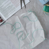 The silk paper square with thread tied to the corners from the Kraul parachute. Kraul offers a range of thoughtful science toys that bring natural forces to life through real-world exploration and play.