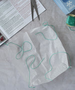 The silk paper square with thread tied to the corners from the Kraul parachute. Kraul offers a range of thoughtful science toys that bring natural forces to life through real-world exploration and play.