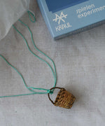 The basket from the Kraul parachute kit tied with the thread onto the silk paper paprachute. The kit contains papers, thread and a mini basket. Kraul offers a range of thoughtful science toys that bring natural forces to life through real-world exploration and play.